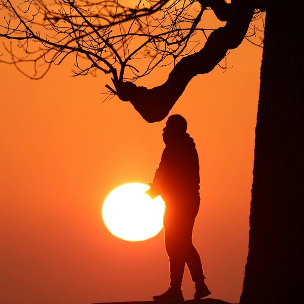 Silhouette of a man stretching against a sunrise, symbolizing energy.